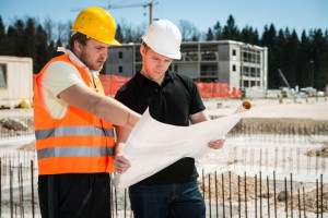 Architect and construction worker reviewing construction plans at construction site